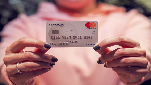 Woman holding Finnair Plus Mastercard - small